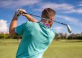 Male golfer taking a swing on a sunny golf course in Boca Raton, Florida.
