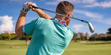Male golfer taking a swing on a sunny golf course in Boca Raton, Florida.
